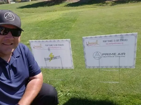 A man sitting on the grass next to some signs.