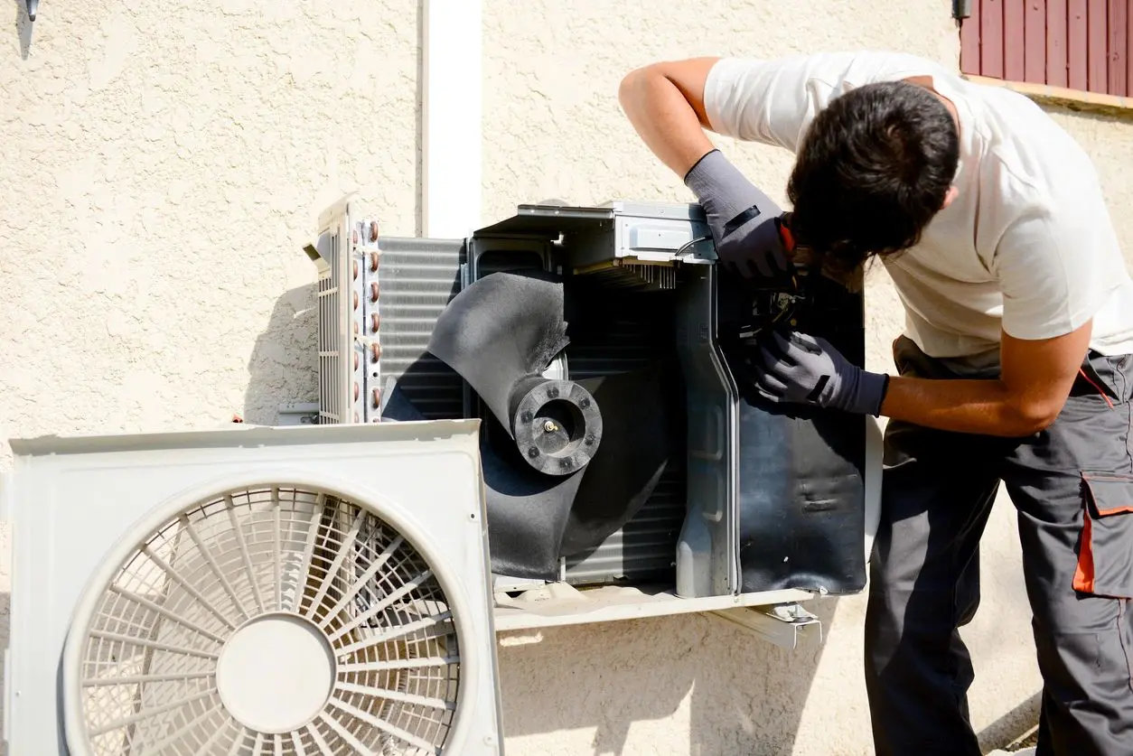 A man working on an air conditioner outside.